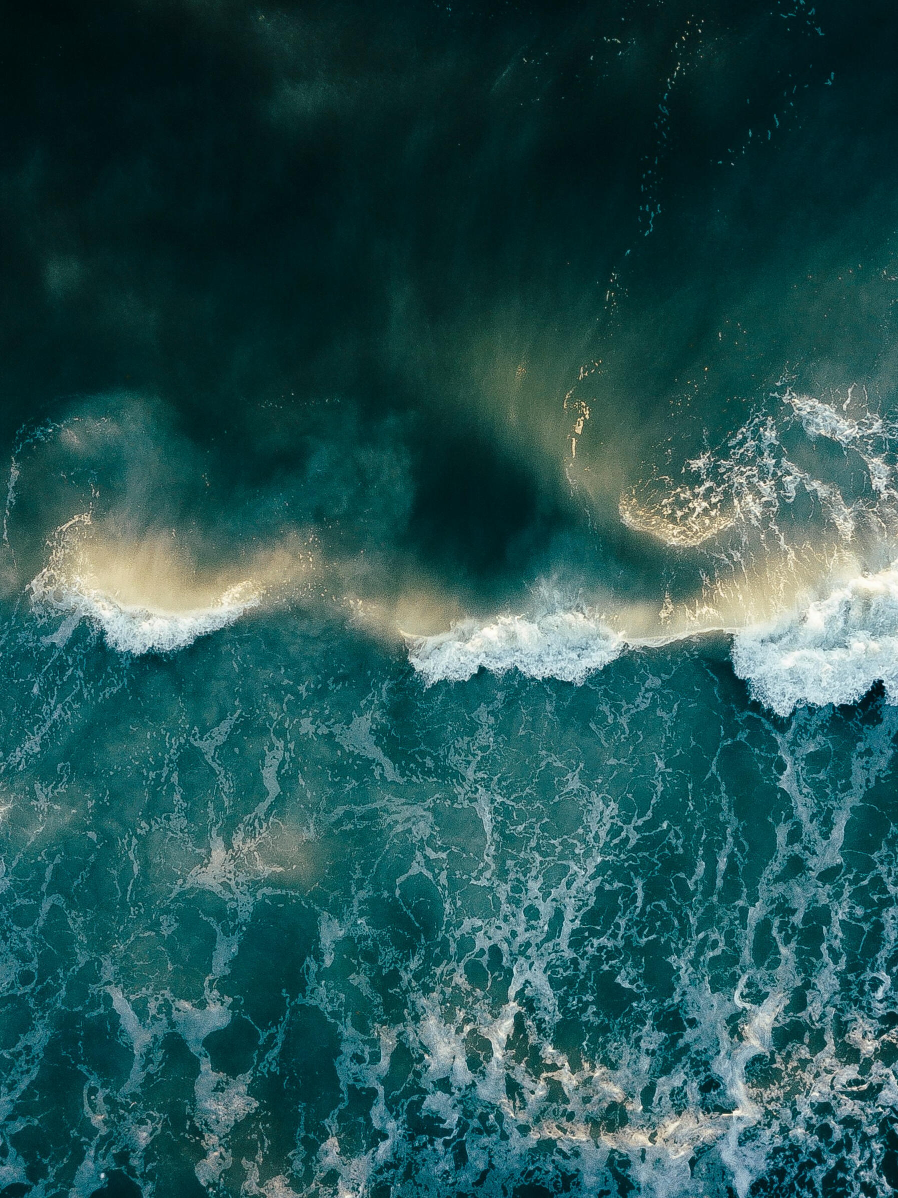 Image by Alex Perez for Unsplash An image of a dark green and teal ocean at sunrise